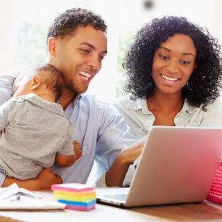 A happy family looking at a laptop together while holding a baby.