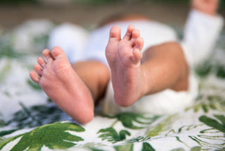 Tiny bare feet resting on floral-patterned fabric.