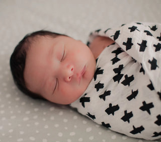 Baby swaddle blanket with black and white geometric pattern, soft cotton material.