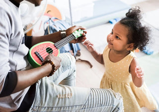 Pink ukulele being played during a music lesson.