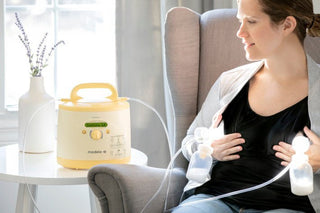 Medela breast pump with yellow casing and dual pumping attachments.